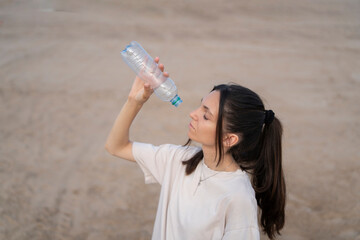 Woman struggling with thirst in a desert holding an empty water bottle