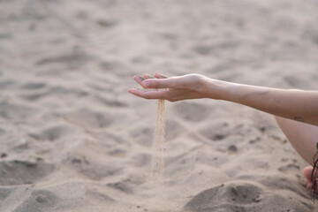Fingers gracefully pouring sand on a beach, capturing fleeting moments of time