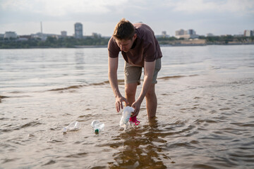 Person collecting plastic waste from the water in an urban river