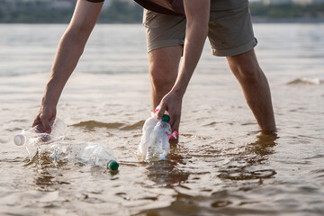 Person collecting plastic waste from the water in an urban river