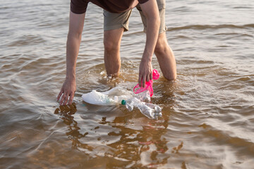 Person collecting plastic waste from the water in an urban river