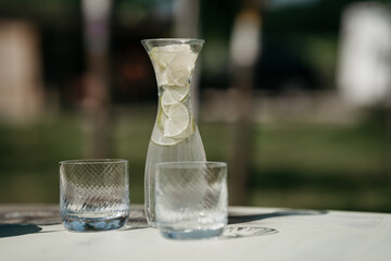 Refreshing lemon water served in a jug and glass on gray table outside