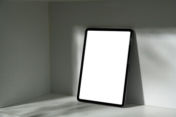 Modern digital tablet with white screen for mockup use on minimalist shelf