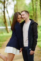 couple embracing on park pathway, enjoying serene nature. woman in navy blazer, man in casual attire. romantic moment in outdoor setting, perfect for love and relationship themes
