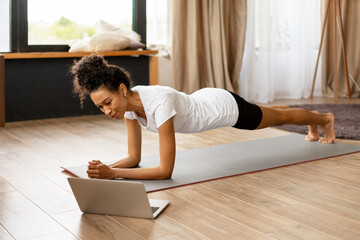 Young woman doing online fitness training at home during quarantine