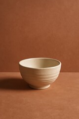 A textured, beige ceramic bowl set against a terracotta background, offering a sense of simple elegance