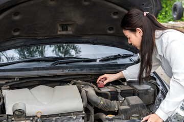 Asian woman driver checking car battery 