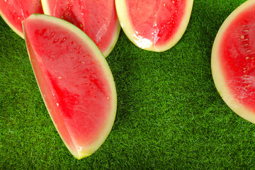 Juicy slices of fresh red watermelon arranged on synthetic grass at a traditional market. The...