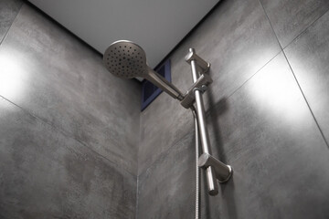 Close-up of a shower head hanging on a rail in a modern bathroom, showcasing sleek design and functionality within a clean and contemporary setting
