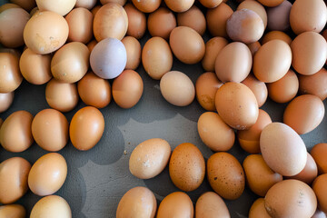 A close-up of a pile of brown chicken eggs with natural imperfections and earthy tones, freshly...