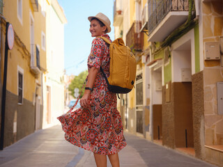 Tourism in Europe. Happy traveler girl visiting the colorful Spanish village with palm trees and...