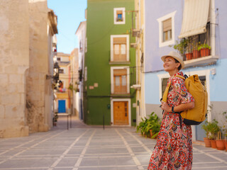 Woman in dress strolls through colorful streets of Spanish coastal town of La Vila Joiosa or...