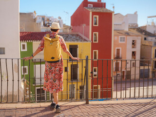 Woman in dress strolls through colorful streets of Spanish coastal town of La Vila Joiosa . sunny...