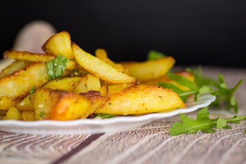Appetizing baked potatoes with garlic and herbs on a black background