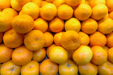 A vibrant pile of fresh mandarin oranges with textured peels displayed in a traditional market. Bright citrus fruits symbolizing freshness, health, and tropical abundance.