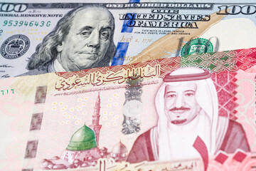 100 US dollar and 100 Saudi riyal banknotes. International trade concept