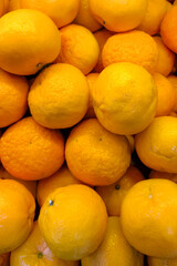 A vibrant pile of fresh mandarin oranges with textured peels displayed in a traditional market. Bright citrus fruits symbolizing freshness, health, and tropical abundance.