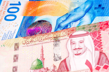 100 Swiss frank and 100 Saudi riyal banknotes. International trade concept