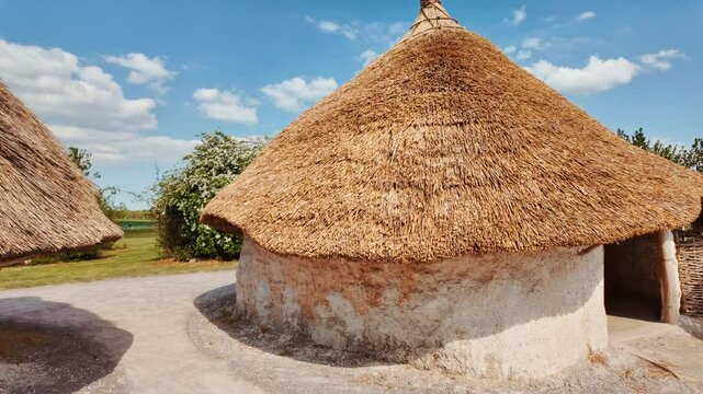 Primitive timber framed huts and earth mounds adjacent to prehistoric stones, Neolithic Houses in Stonehenge, Salisbury, Wiltshire, England, UK