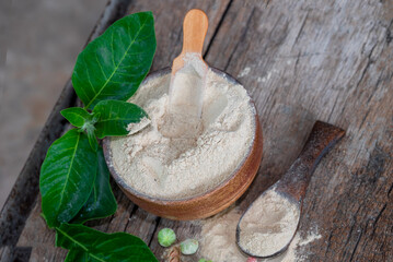 Withania somnifera (Ashwagandha) dried root Powder, green leaves Medicinal Herb. Ashwagandha on wooden background
