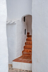Curved Terracotta Staircase Within Whitewashed Archway in Binibeca Vell. Menorcan Architecture, Hidden Alley, Traditional Mediterranean Design