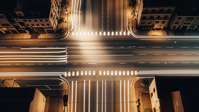 Aerial night view of a city intersection illuminated by long exposure vehicle light trails