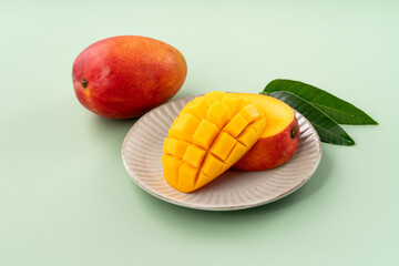 Fresh ripe mango with cubes on green table background.