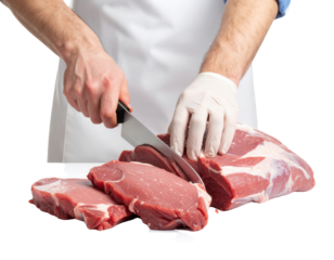 A person wearing a white apron and glove slices fresh raw beef with a large knife into thick pieces.