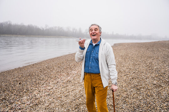 Cheerful man talking on mobile phone through speaker at beach
