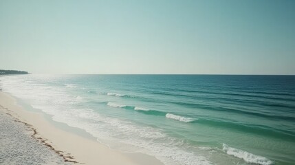 Obraz premium Wide beach scene, gentle waves, pale sand, clear sky