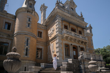 A woman stands in front of a large building with a stone facade