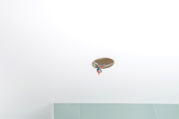 white stretch ceiling with a hole for lighting, with faulty wiring in the hole