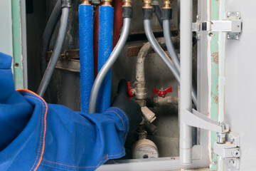 a uniformed worker shuts off a water pipe in an apartment for non-payment of housing and communal services