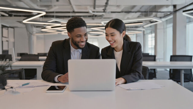 A couple sitting together looking at a laptop, possible romantic moment or business discussion