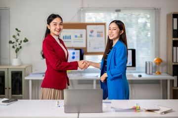 Fototapeta premium Two businesswomen shaking hands after closing a business deal in the office