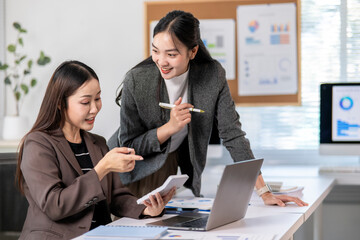 Businesswomen working together using calculator and laptop in office