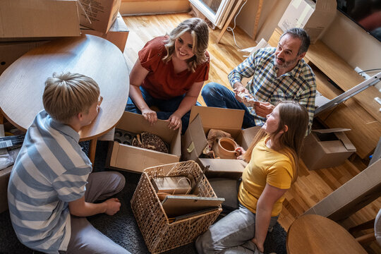 	
A family is moving into a new apartment, unpacking boxes together in the living room. They organize their belongings and start setting up their new home.	
