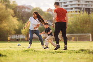 Running, playing soccer. Family of mother, father and son are playing on the field