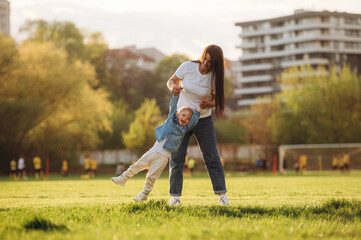 Cheerful, having fun, holding boy in hands. Mother and son are together on the summer field