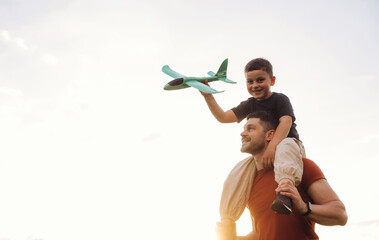 Imagination conception. Boy is with toy plane. Father and son are having fun outdoors