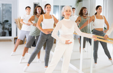 Fototapeta premium Group of people of different ages practice ballet moves in classical dance school.