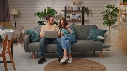 Fototapeta premium Couple Celebrating Successful Online Purchase Together on Sofa