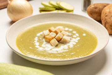 Zucchini, onion and potato soup served on beige dish