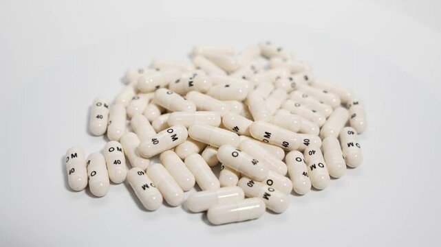 Capsule Heap from Above. A top-down view shows rotating white capsules densely packed together. Focus is on quantity and surface texture.
