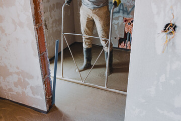 Construction worker leveling concrete surface flooring using a bull float