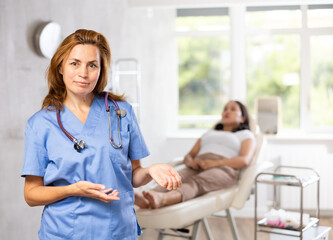 Obraz premium Smiling woman beautician wearing blue overall posing in clinic of esthetic medicine