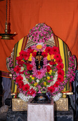 Decorated Hindu Deity Idol with Floral Garland and Ornate Background