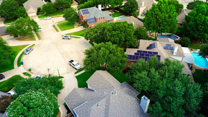 Circle cul-de-sac street with row of homes has rooftop solar panel arrays, angled installations for...