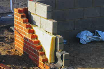 Insulating walls of new build houses by placing rock wool inside wall cavities as part of the...