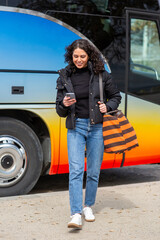 Full body smiling travel woman walking with bag while looking at her phone.